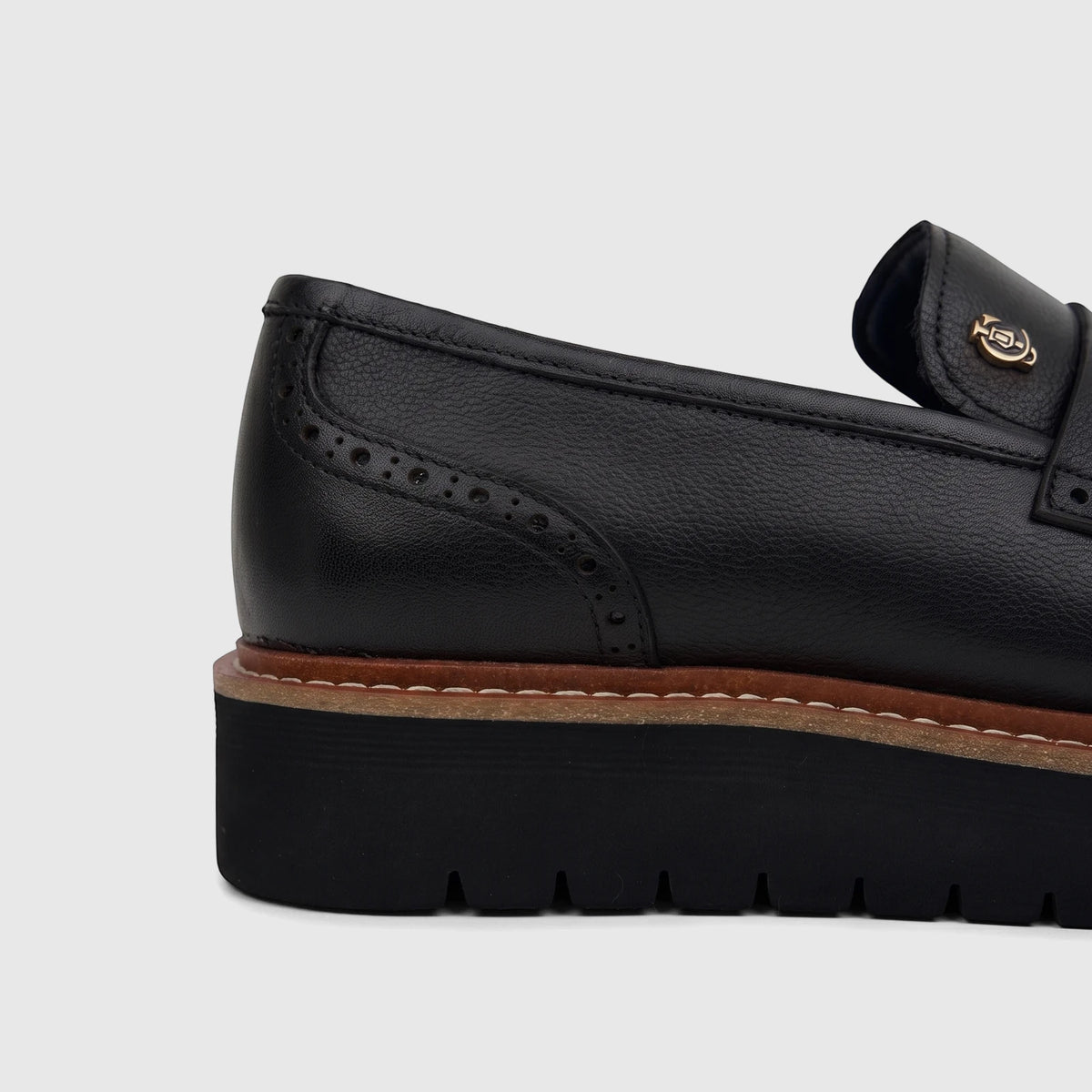 Close-up of a black pebbled leather Crockett And Jones men's chunky sole loafer with brogue details.