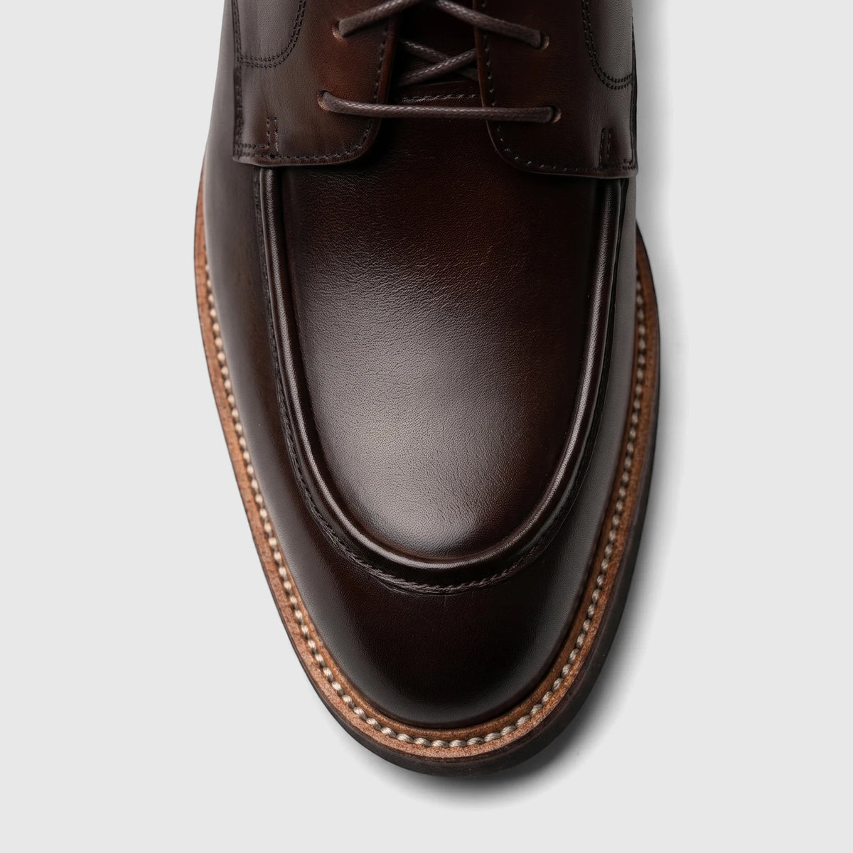 Close-up of a Crockett And Jones Guilio men's lace-up shoe in dark brown polished leather, MOC toe style.