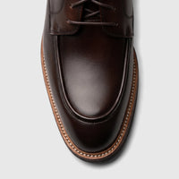Close-up of a Crockett And Jones Guilio men's lace-up shoe in dark brown polished leather, MOC toe style.