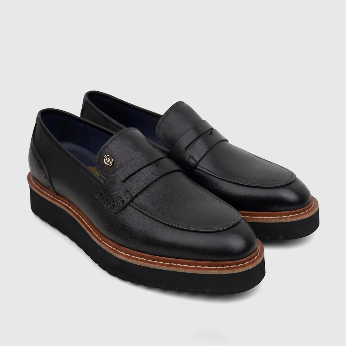 Pair of Crockett And Jones men's black leather chunky sole loafers with gold emblems, shown from an angled view.