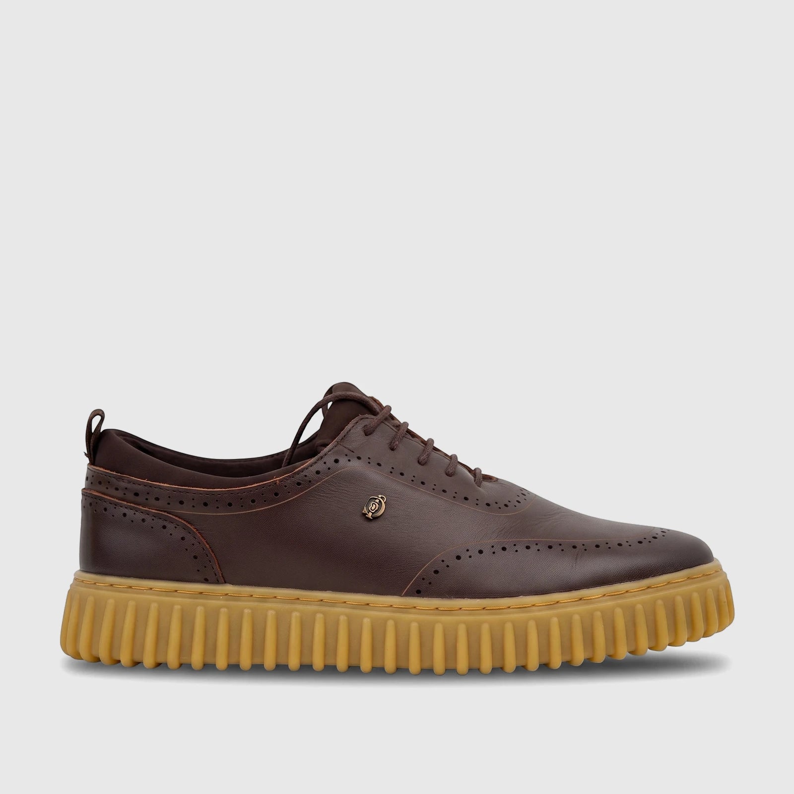 Brown leather men's lace-up shoe with brogue details and a chunky tan ribbed sole, viewed from the side.