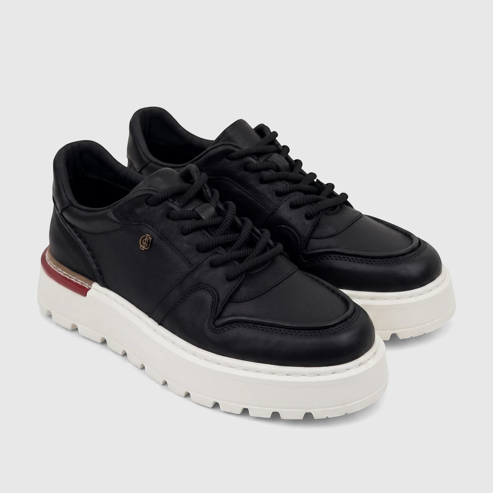 Pair of Crockett and Jones Men's Tino black leather sneakers with white platform soles and black laces, angled view.