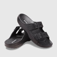 A pair of black Crocs Saturday Sandals, featuring two adjustable straps with buckles, shown from a slightly elevated view on