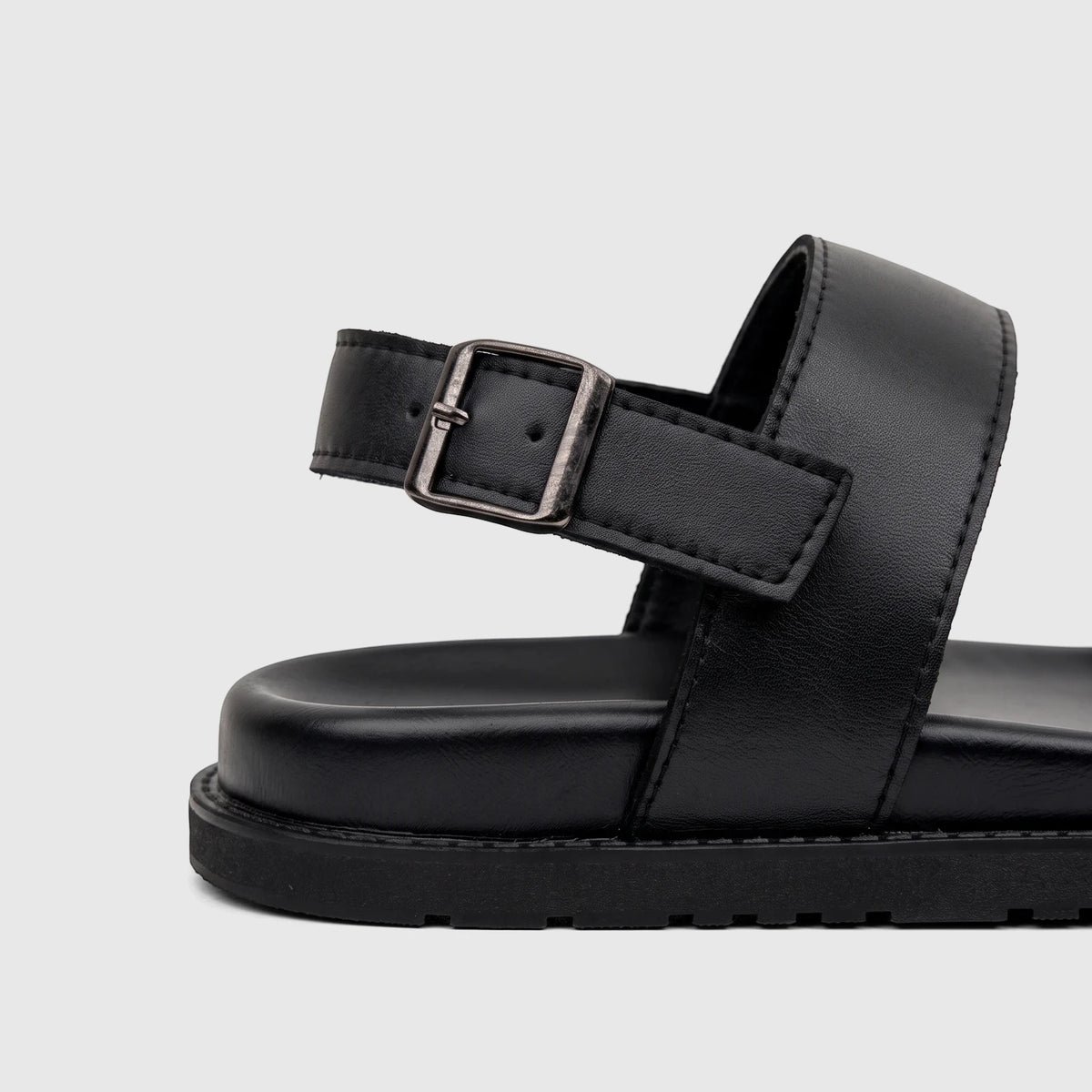 Close-up view of a black Fabino men's leather comfort sandal, highlighting the textured sole and metal buckle details.