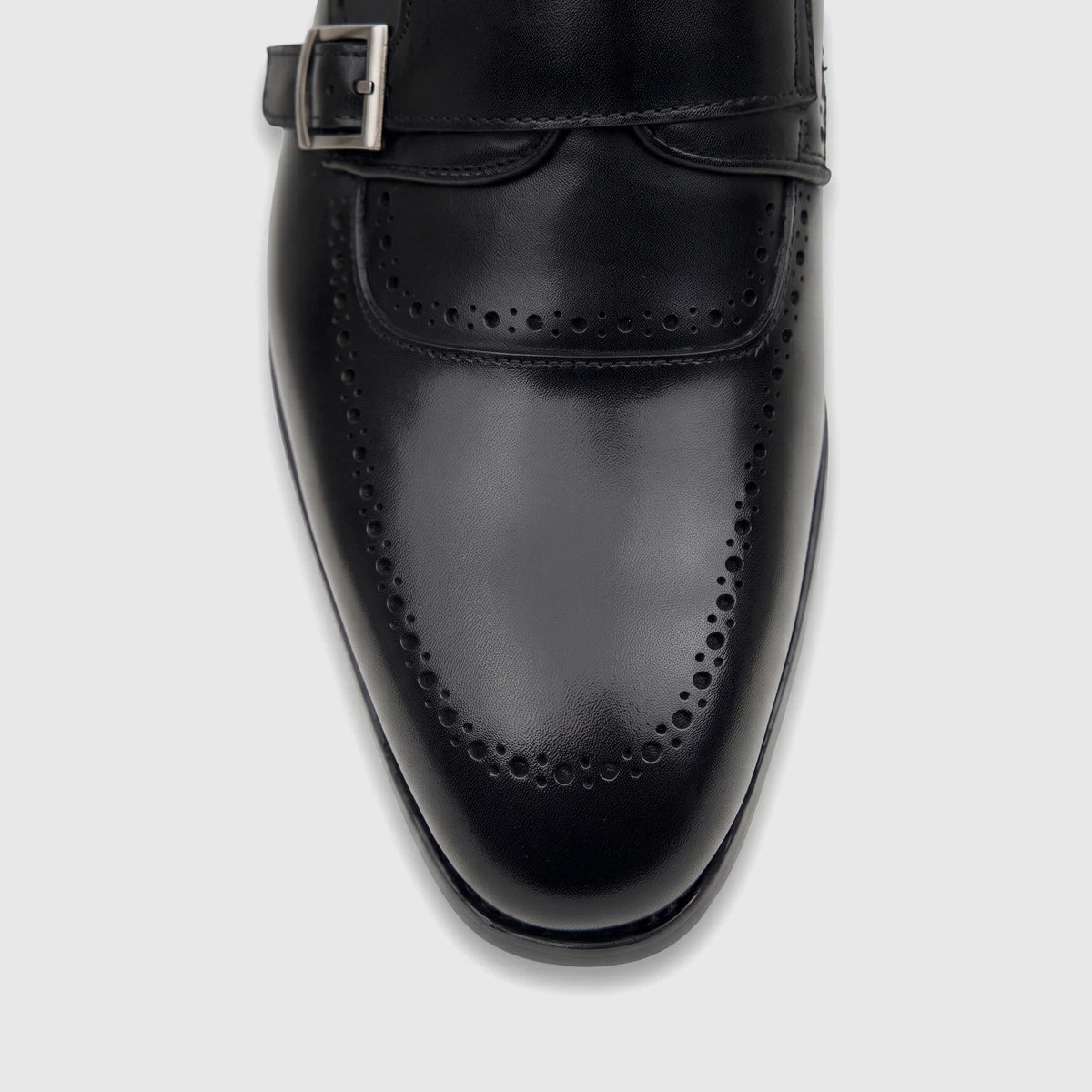 Close-up of a men's black leather double monk strap dress shoe with brogue detailing and a silver buckle.