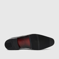 Fabino men's black leather dress shoe, showcasing the textured rubber sole and the elegant red-brown arch with brand