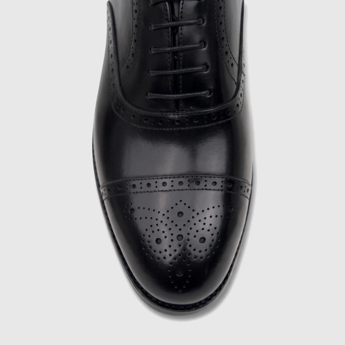 Overhead view of a glossy Fabino Men's black leather lace-up dress shoe with intricate brogue detailing on the cap toe.