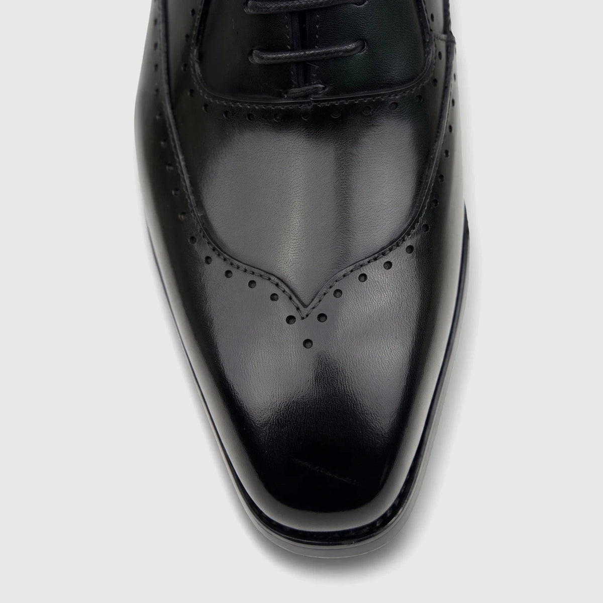 Close-up of a black leather men's lace-up dress shoe with subtle broguing on the toe, from Fabino.