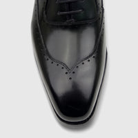 Close-up of a black leather men's lace-up dress shoe with subtle broguing on the toe, from Fabino.