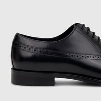 Close-up of a men's black leather lace-up dress shoe from Fabino, featuring elegant brogue detailing on the side and a