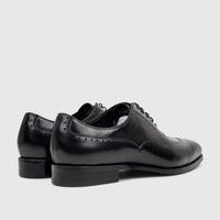 Black leather lace-up men's dress shoes, featuring classic brogue detailing and a polished finish, seen from a slight