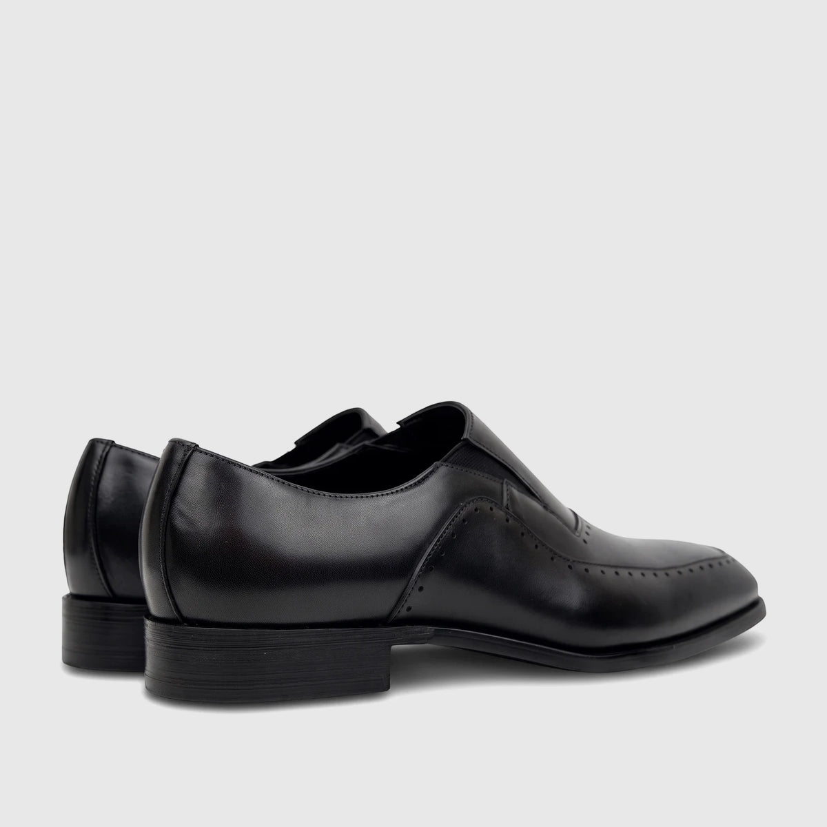 Pair of black leather men's slip-on dress shoes, showcasing a sleek design with perforated details and low heels from a side