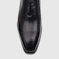 Close-up top view of a Fabino Men's black patent leather lace-up dress shoe, highlighting the glossy finish and brogue