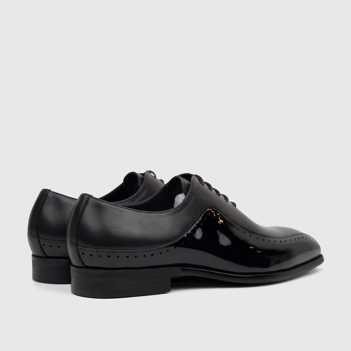 Rear view of two men's Fabino M3220239 black patent leather lace-up dress shoes, featuring brogue detailing.