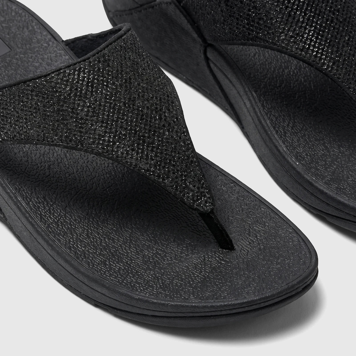 Close-up of two black Fit Flop Ladies Comfort Sandal Lulu Shimmerglitz, featuring textured straps and a comfortable sole.