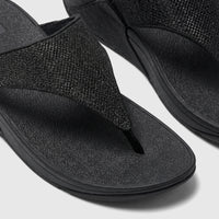 Close-up of two black Fit Flop Ladies Comfort Sandal Lulu Shimmerglitz, featuring textured straps and a comfortable sole.