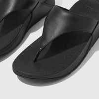A close-up view of black Fit Flop Lulu leather comfort sandals, featuring a thong-style strap and a platform sole.