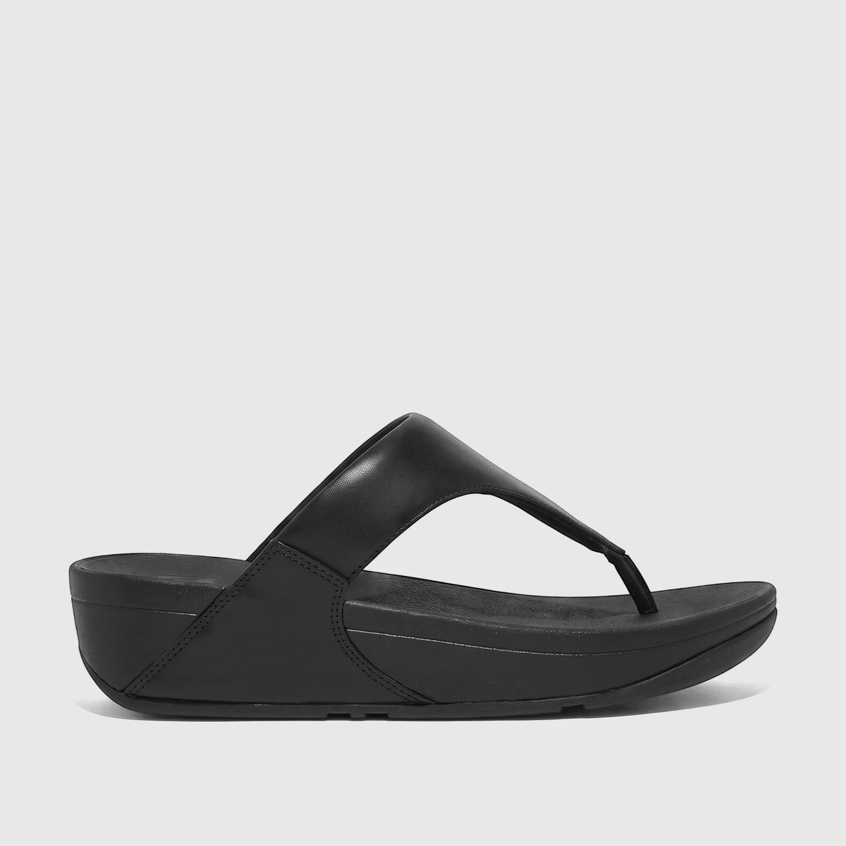 Black Fit Flop Lulu leather comfort thong sandal with a thick platform sole, viewed from the side on a light background.