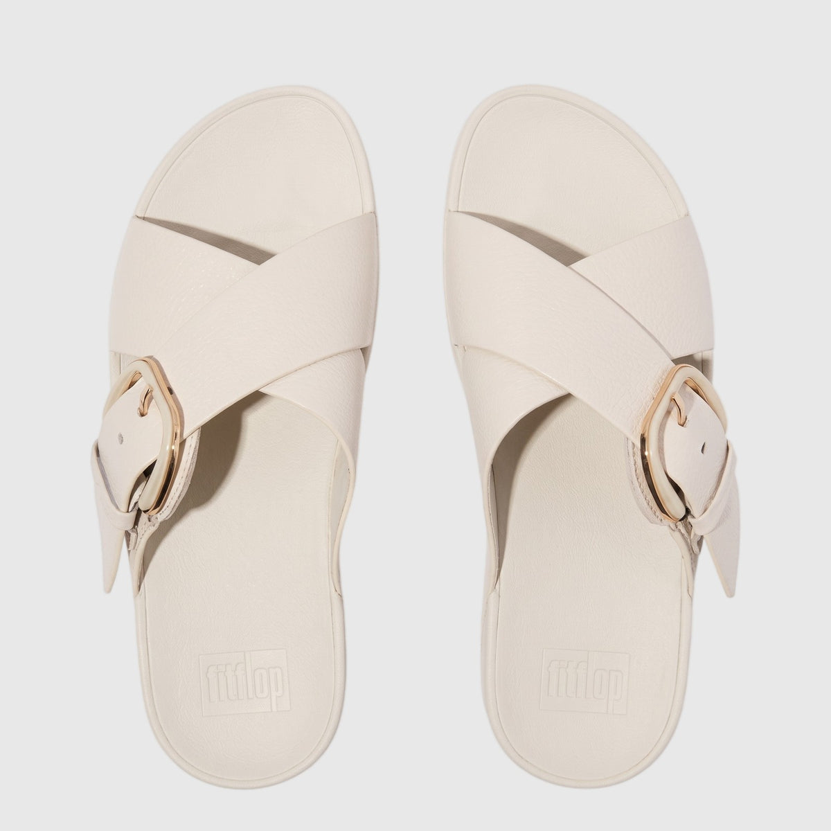Off-white Fit Flop Lulu Resin Buckle Leather Cross Slide sandals, flat lay view, featuring criss-cross straps and a