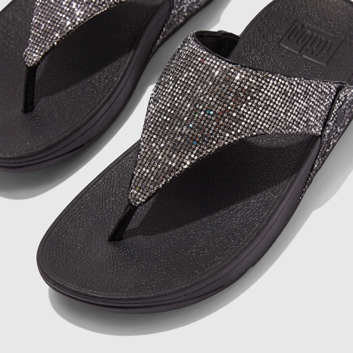 Close-up of two black FitFlop Lulu Glitterball comfort sandals with sparkling silver straps and black soles.