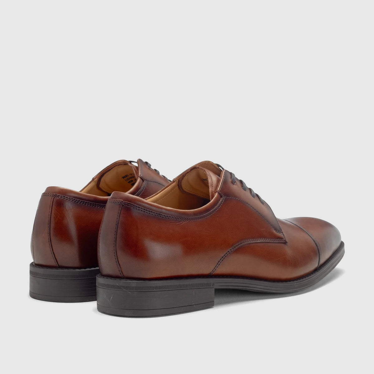 A pair of Florsheim Men's Comfortech Chateau cap-toe lace-up dress shoes in cognac brown leather, viewed from the rear-side.