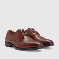 A pair of cognac brown Florsheim Men's Comfortech Chateau lace-up dress shoes, featuring a cap toe design, displayed at a