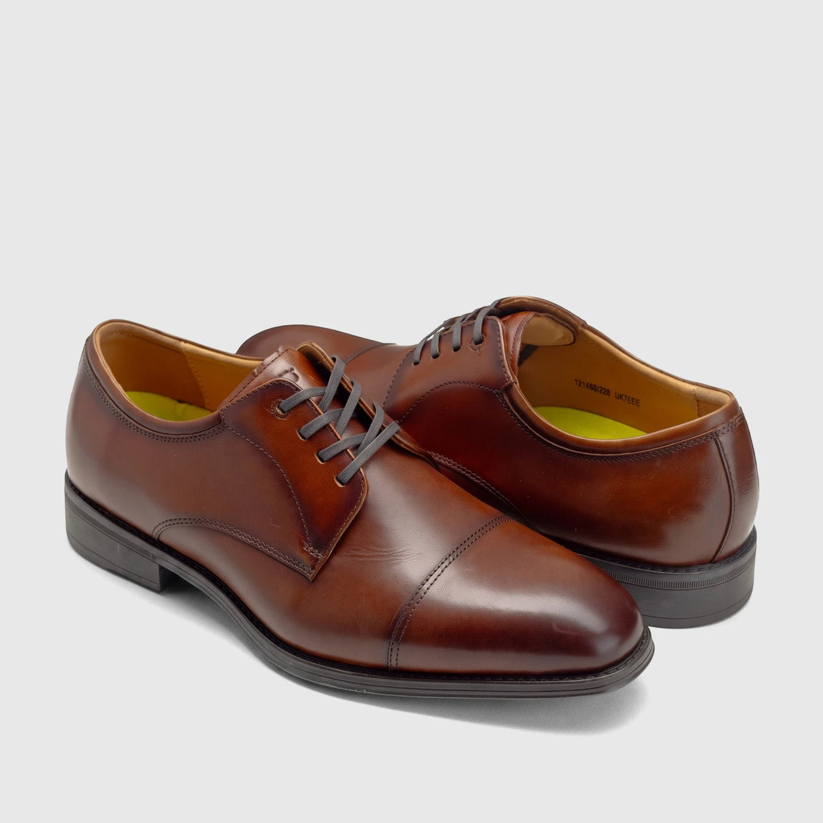 A pair of Florsheim Men's Comfortech Dress Lace Up Chateau shoes in rich cognac leather, featuring a cap-toe design and dark
