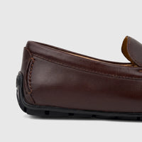 Close-up side view of a dark brown leather Florsheim Men's Loafer Motor Moc shoe with detailed stitching and a black rubber