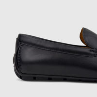 Close-up of a black leather men's Florsheim Motor Moc loafer, showcasing the textured leather and stitched details from the
