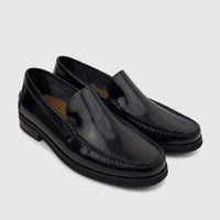 A pair of shiny black leather Florsheim Men's Slip On Berkley Flex Venetian loafers with visible stitching, angled on a