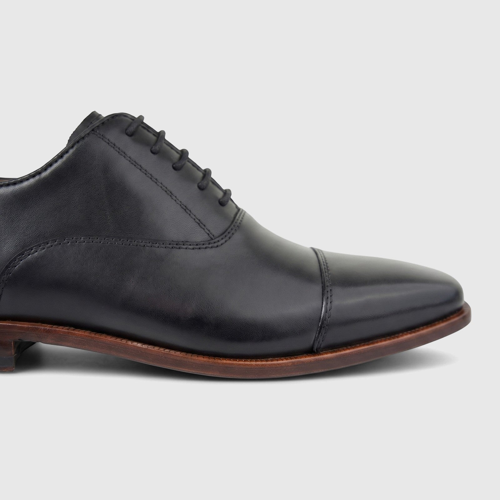 Formales men's black leather cap-toe lace-up dress shoe shown in a close-up side view, highlighting the smooth leather and