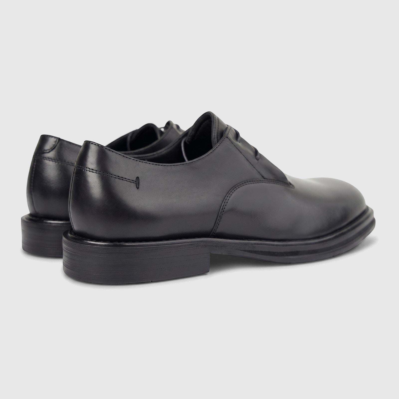 A pair of black leather men's derby shoes with a chunky sole, viewed from a rear-quarter angle on a white background.