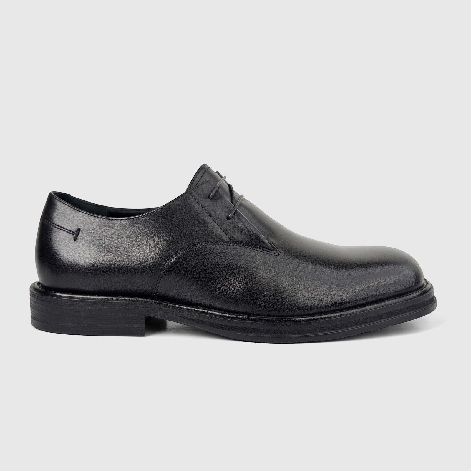 Black leather men's formal dress shoe with a chunky sole and subtle lacing, presented in a side profile view.