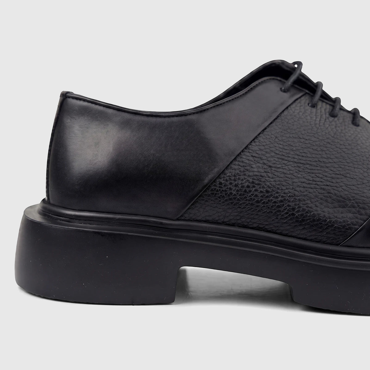 Close-up profile view of a Formales men's black leather chunky sole lace-up shoe with textured and smooth panels.