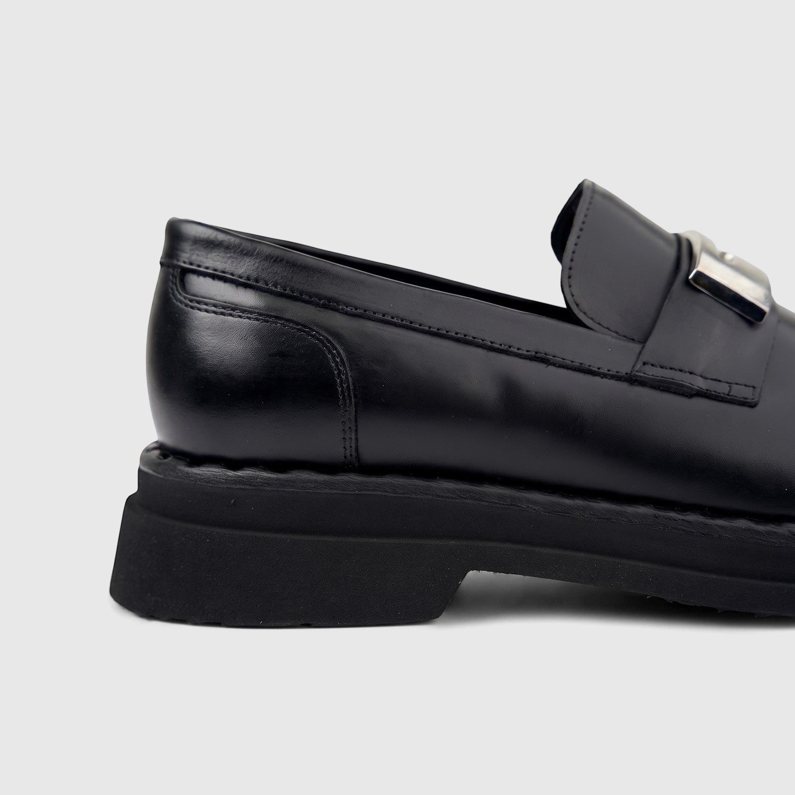 Close-up side view of a Formales Men's black leather chunky sole slip-on loafer with a silver buckle detail.