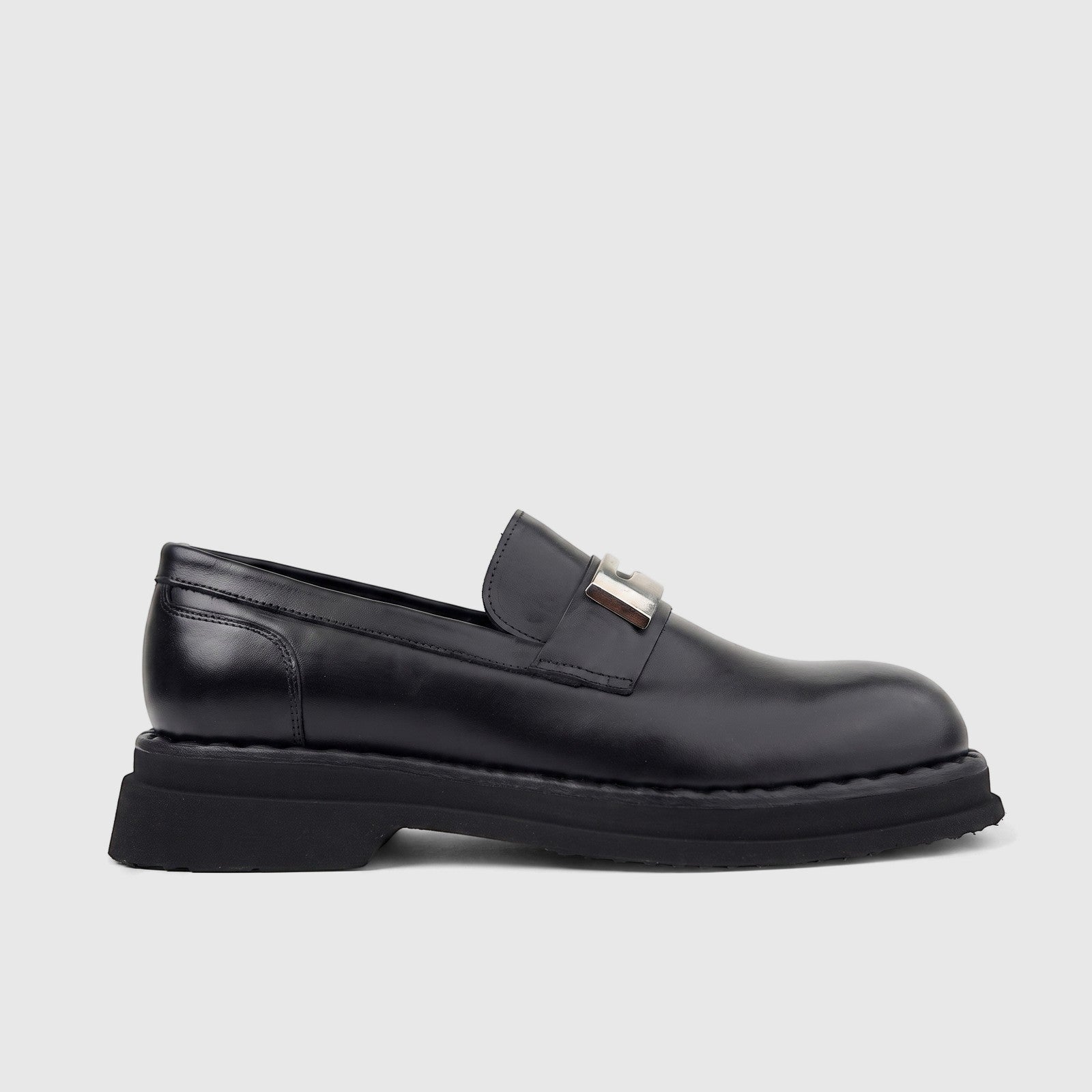 Men's Formales black leather chunky sole slip-on loafer shoe with a silver-toned buckle, viewed from the side.