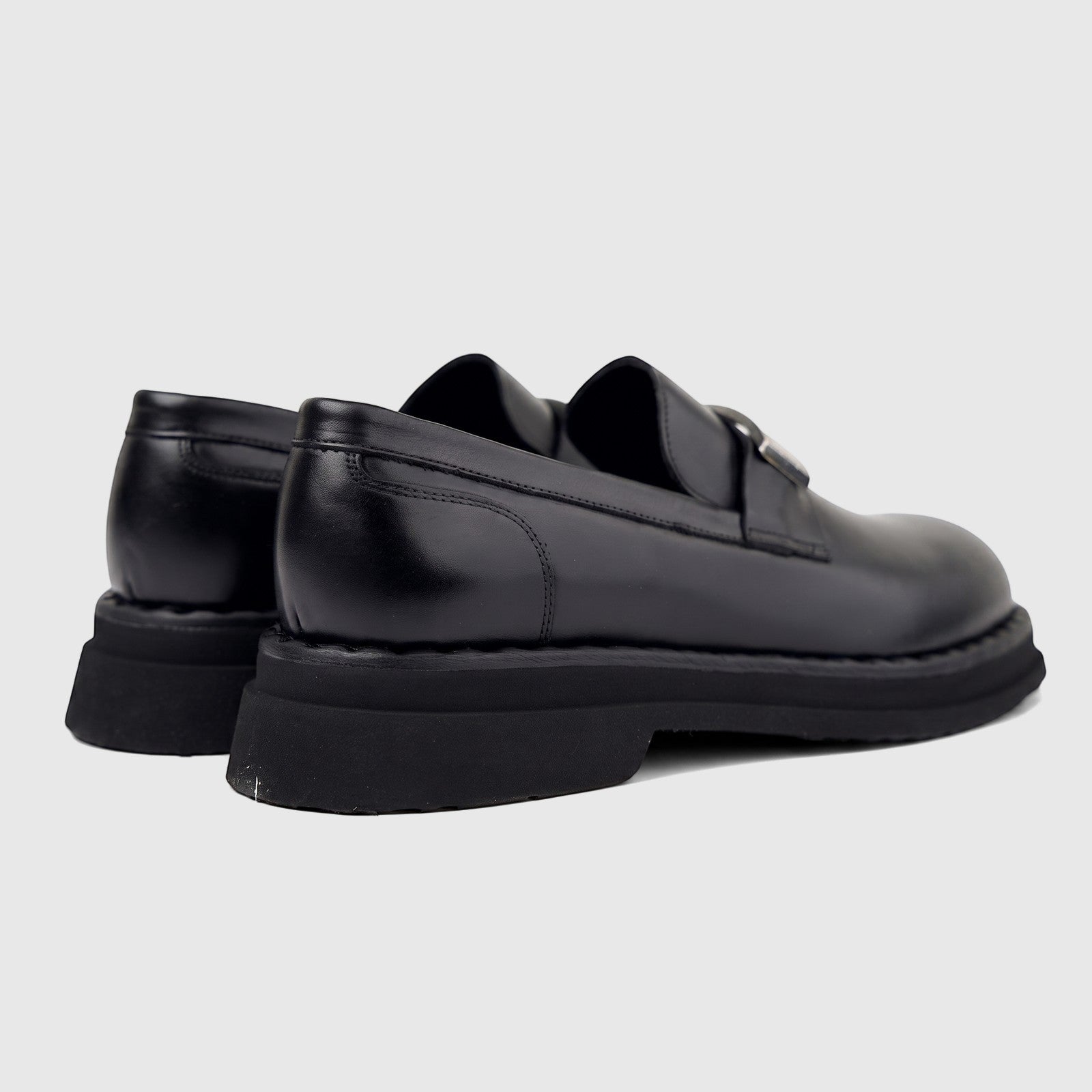 Pair of Formales Men's black leather chunky sole slip-on loafers, viewed from the rear side, showcasing the thick rubber