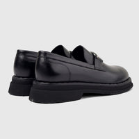 Pair of Formales Men's black leather chunky sole slip-on loafers, viewed from the rear side, showcasing the thick rubber