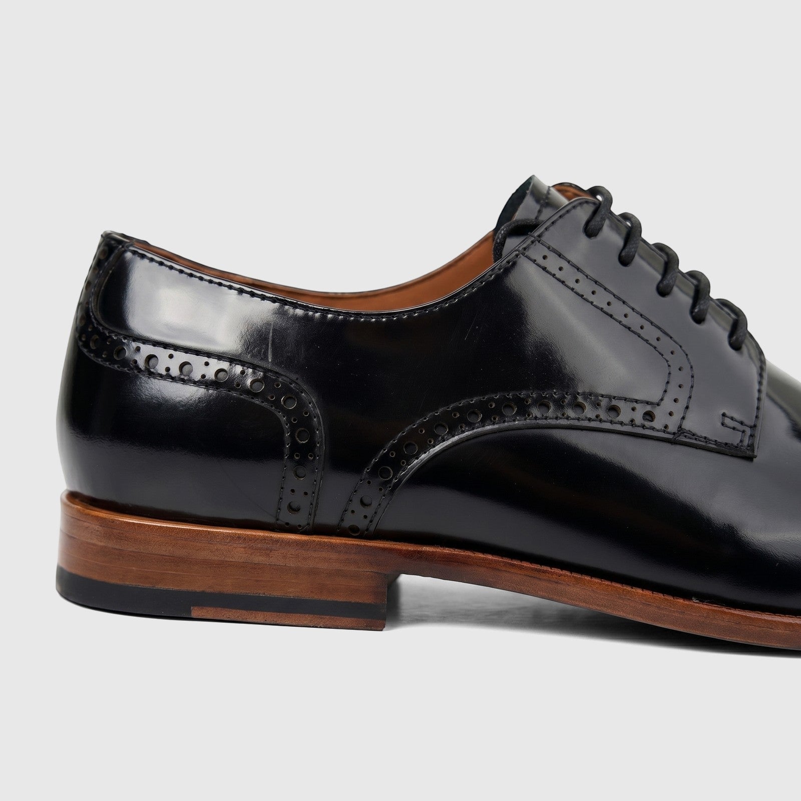 Close-up side view of a Formales men's black leather lace-up dress shoe with detailed broguing and a distinct brown sole.