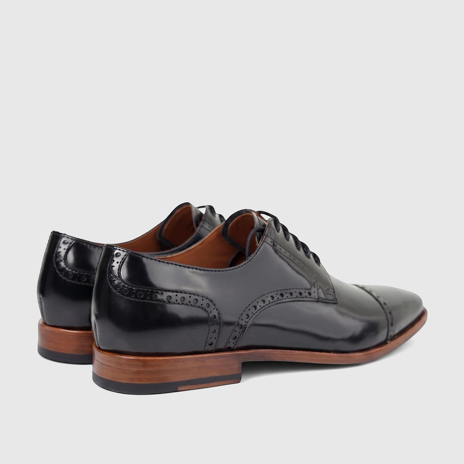 Formales men's black leather lace-up dress shoes, featuring brogue details and brown stacked heels, captured in a rear-side