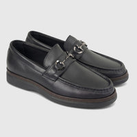 A pair of men's black leather loafers, featuring gunmetal horsebit hardware on the vamp and a visible brown sole trim,