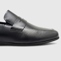 Close-up side view of a Formales men's black leather slip-on shoe, featuring smooth leather and a penny loafer strap.