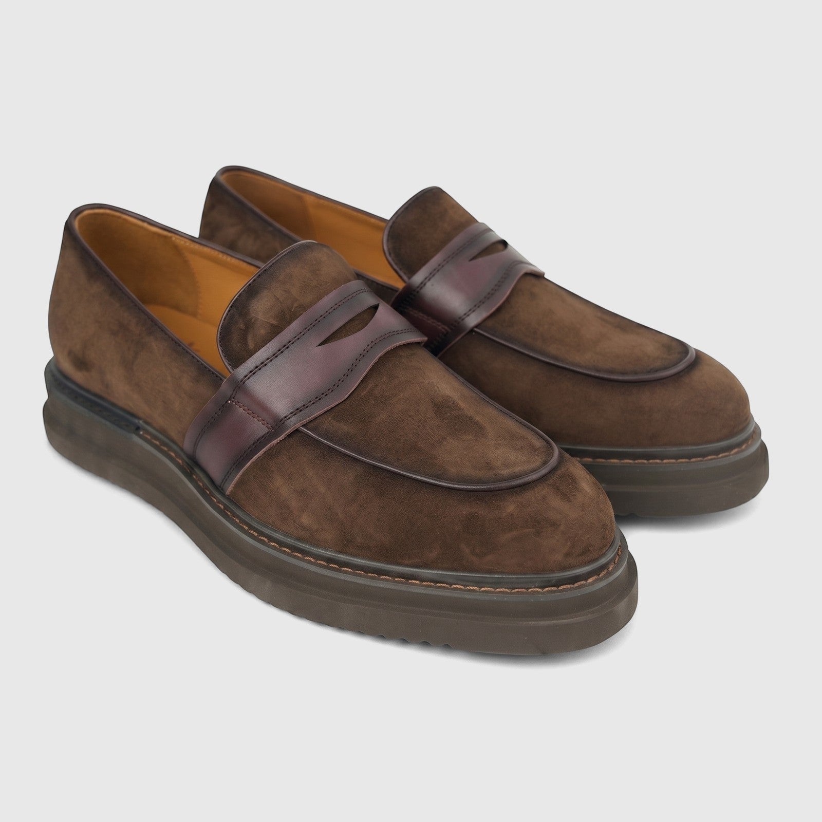 A pair of Formales Men's Leather Chunky Sole Slip On shoes in coffee brown suede with burgundy leather straps.