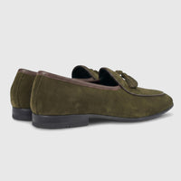 A pair of Formales Men's green suede loafers with brown piping and tassels, viewed from a rear-side angle on a white