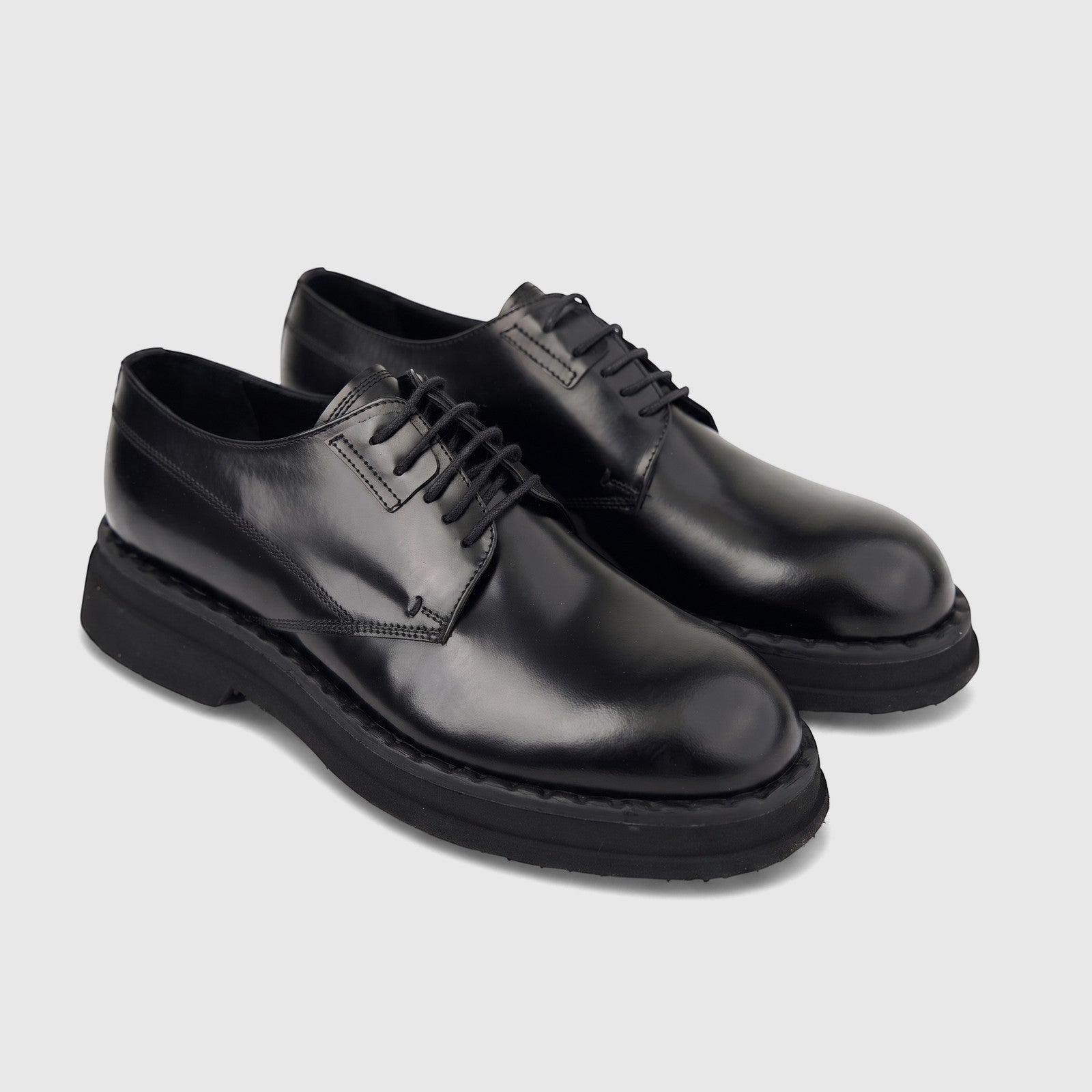 Pair of black hi-shine leather formal shoes with chunky soles and lace-up closure, presented from a front-quarter view.