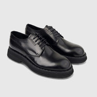 Pair of black hi-shine leather formal shoes with chunky soles and lace-up closure, presented from a front-quarter view.