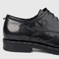 Close-up of a black leather men's formal shoe with chunky sole and lace-up design, shown from the side.
