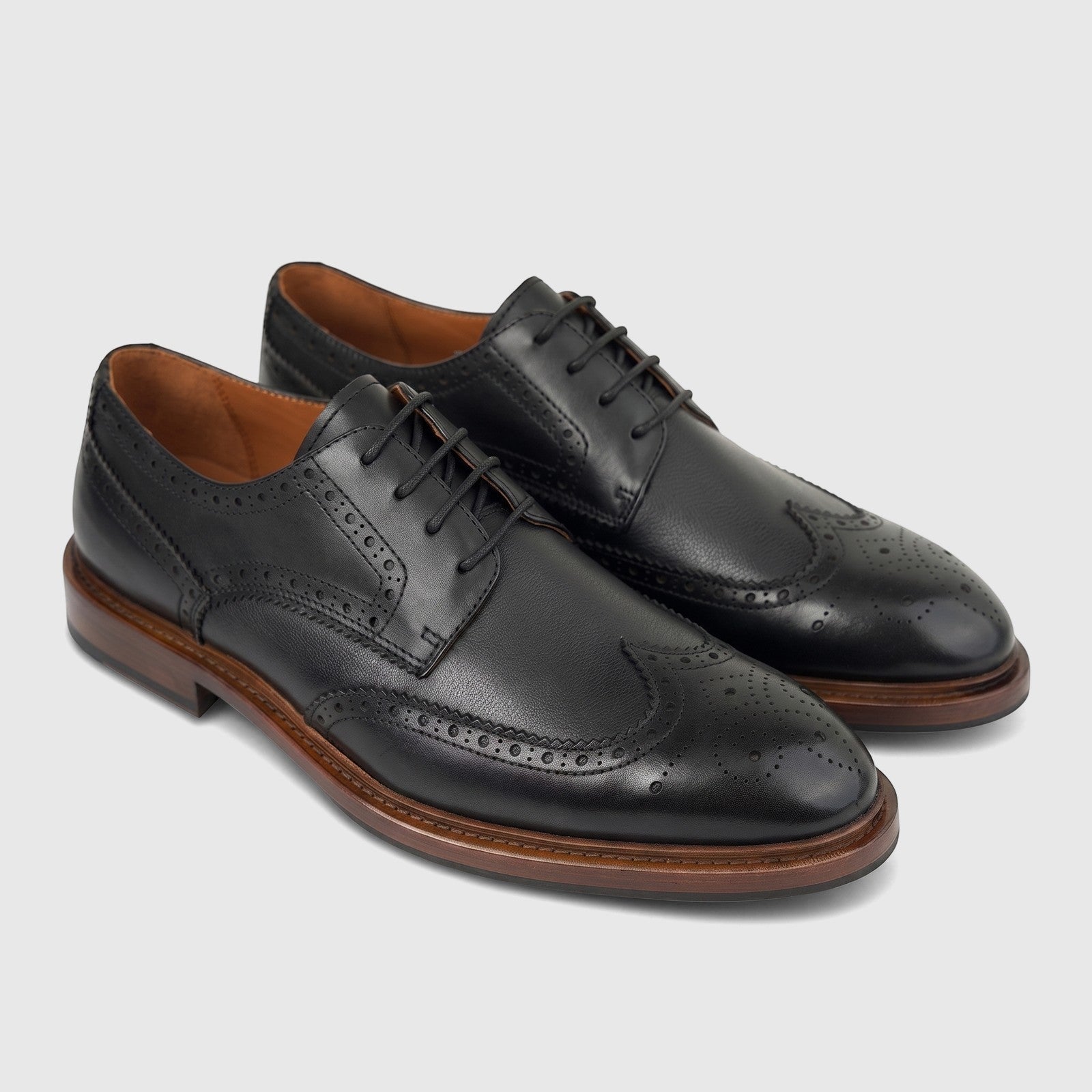 A pair of black Formales men's leather lace-up shoes with brogue details and chunky brown soles, viewed from an angle.