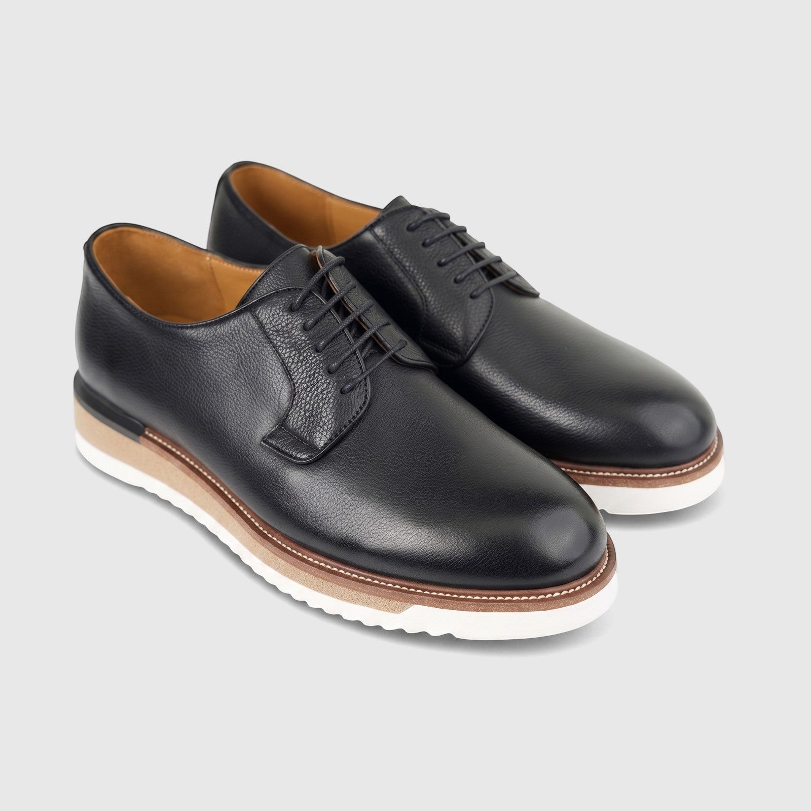 Pair of Formales men's black textured leather lace-up shoes with chunky white and brown soles, photographed from a high
