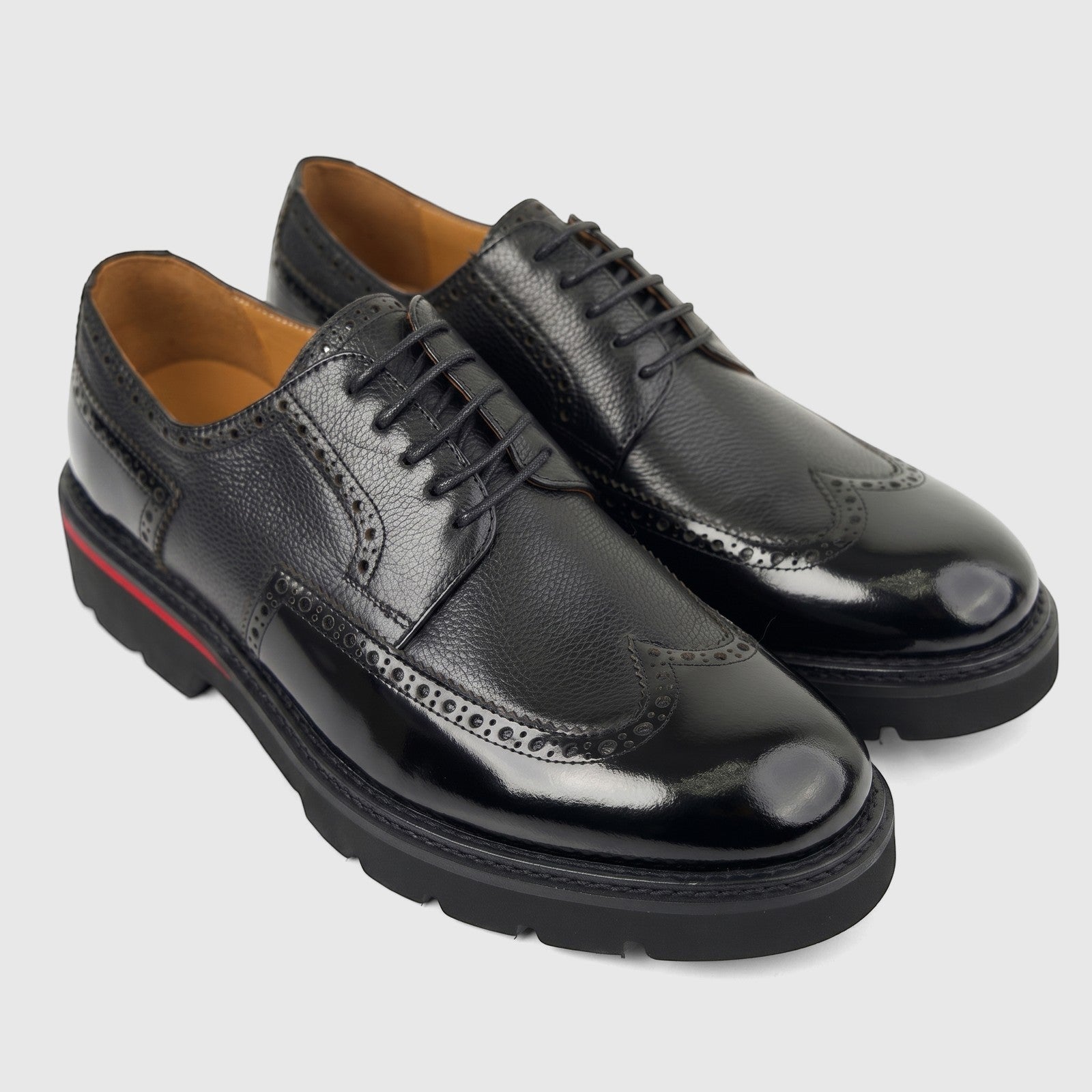 Black formal men's leather lace-up shoes with chunky soles and wingtip brogue detailing, viewed from an elevated angle.